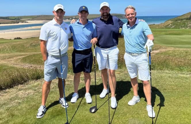Four golfers standing together on a links course at St Enodoc with the estuary behind them