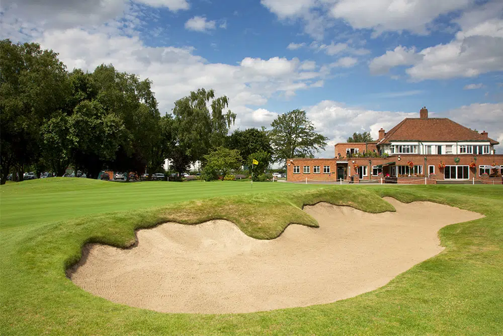 The red-brick clubhouse at Fulford Golf Club seen across a green and a large greenside bunker