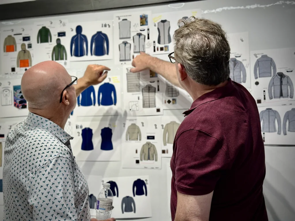 Turtleson co-founders Greg Oakley and Chet Sikorski pointing at clothing design sketches pinned to a wall