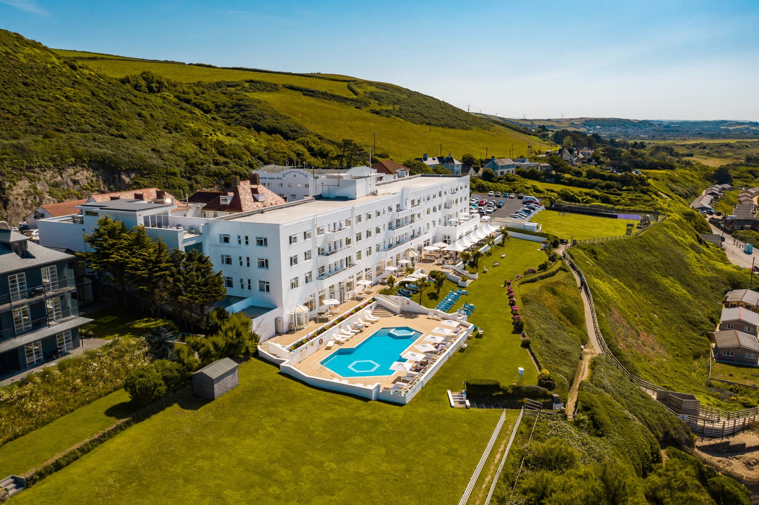 Aerial view of the white Saunton Sands Hotel with its outdoor pool and lawns on the North Devon coast