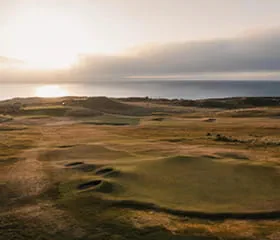 Aerial view of a coastal links course at sunset