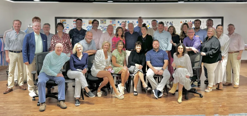 Group photo of the Turtleson team in their office, standing and seated in front of a wall of design boards